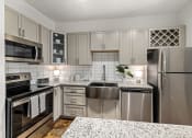 Thumbnail 2 of 18 - a kitchen with white cabinets and granite countertops