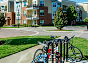 Thumbnail 11 of 33 - A blue bicycle is parked next to a red bicycle on a sidewalk.