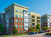 Thumbnail 32 of 33 - Apartment complex with a parking lot in front.