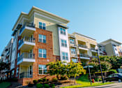 Thumbnail 31 of 33 - A multi-story apartment building with balconies and a clear blue sky above.