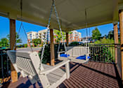 Thumbnail 16 of 33 - A porch swing hangs from a chain on a wooden porch.