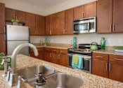 Thumbnail 2 of 33 - A kitchen with brown cabinets and a granite countertop.