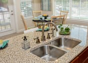 Thumbnail 6 of 33 - A kitchen with a granite countertop and a stainless steel sink.