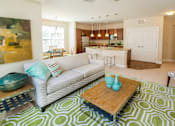 Thumbnail 5 of 33 - A living room with a couch, coffee table, and a patterned rug.
