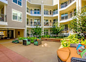 Thumbnail 21 of 33 - A courtyard with a couch and chairs surrounded by apartment buildings.