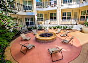 Thumbnail 20 of 33 - A patio with chairs and a fire pit in the middle of a courtyard.