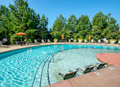 Thumbnail 15 of 33 - A large outdoor swimming pool with a wooden deck and lounge chairs.