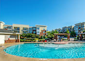Thumbnail 1 of 33 - A large swimming pool in front of apartment buildings.