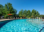 Thumbnail 12 of 33 - A large swimming pool with a blue tinted water and a sun umbrella.