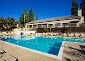 Thumbnail 8 of 27 - A swimming pool in front of a house with a blue sky.