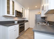 Thumbnail 25 of 27 - A modern kitchen with white cabinets and stainless steel appliances.