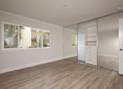 Thumbnail 24 of 27 - A room with wooden flooring and a large window with a view of a building outside.