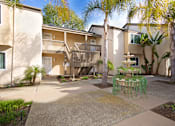 Thumbnail 5 of 27 - A courtyard with a fountain surrounded by palm trees and apartment buildings.