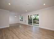 Thumbnail 23 of 27 - A room with wooden flooring and a sliding glass door leading to a backyard.
