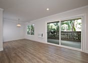 Thumbnail 22 of 27 - A room with a sliding glass door and wooden flooring.