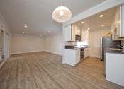 Thumbnail 19 of 27 - A kitchen with a wooden floor and white cabinets.