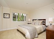 Thumbnail 27 of 27 - A bedroom with a large bed and a picture on the wall.