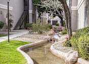 Thumbnail 31 of 39 - A small pond with rocks and a tree in front of a building.at Vintage at Scottsdale, SCOTTSDALE, AZ