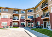 Thumbnail 21 of 22 - Apartment building with a parking lot in front.