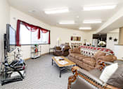 Thumbnail 18 of 22 - A living room with a brown leather couch and a television.