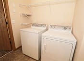 Thumbnail 7 of 22 - Two white front loading washing machines in a laundry room.