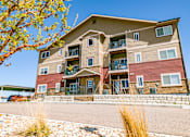 Thumbnail 1 of 22 - A large apartment building with a red and beige exterior and a balcony on the second floor.