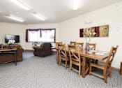 Thumbnail 2 of 22 - A living room with a brown couch, a brown chair, a wooden table and chairs, and a television.
