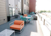 Thumbnail 26 of 26 - a patio with orange and blue chairs and tables on a balcony