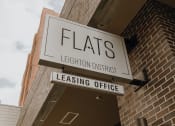 Thumbnail 18 of 26 - a leasing office sign on the side of a brick building