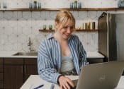 Thumbnail 13 of 26 - a woman sitting at a kitchen counter using a laptop computer