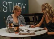 Thumbnail 17 of 26 - two women sitting at a table with their laptops