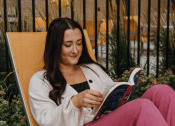Thumbnail 22 of 26 - a woman sitting in a chair reading a book