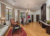 Thumbnail 4 of 22 - A living room with a white sofa, a brown chair, a black coffee table, and a red rug.