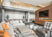 Thumbnail 4 of 20 - A modern living room with a grey couch and a wooden entertainment center.