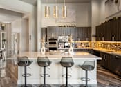 Thumbnail 6 of 32 - A modern kitchen with a bar area and a dining table.
