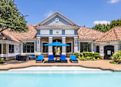 Thumbnail 8 of 22 - A pool area with a building and blue loungers.