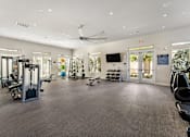Thumbnail 10 of 32 - A spacious gym with a variety of equipment and a ceiling fan.