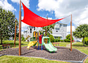 Thumbnail 11 of 22 - A playground with a yellow slide and a red shade sail.