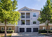 Thumbnail 12 of 22 - A two-story apartment building with a garage door and balcony.