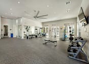 Thumbnail 12 of 32 - A spacious gym with a variety of equipment and mirrors on the walls.