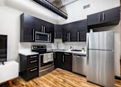 Thumbnail 12 of 21 - A kitchen with black cabinets and a stainless steel refrigerator - The Kirby