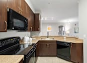 Thumbnail 15 of 22 - A kitchen with black appliances and brown cabinets.