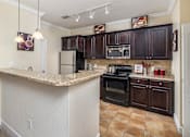 Thumbnail 15 of 22 - A kitchen with brown cabinets and a granite counter.