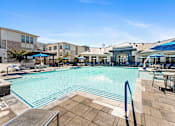 Thumbnail 15 of 32 - A large swimming pool surrounded by a tiled patio and lounge chairs.