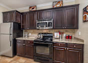 Thumbnail 16 of 22 - A kitchen with dark brown cabinets and stainless steel appliances.