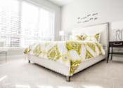 Thumbnail 16 of 20 - A bed with a yellow and white comforter sits in a bright bedroom.