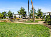 Thumbnail 18 of 32 - A grassy area with a tree and a sign in the background.