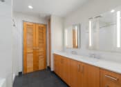Thumbnail 20 of 36 - a bathroom with two sinks and a shower and wooden doors