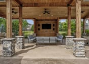 Thumbnail 19 of 36 - a covered patio with stone pillars and a fireplace