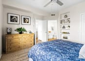 Thumbnail 20 of 23 - A bedroom with a blue bedspread and a wooden dresser.